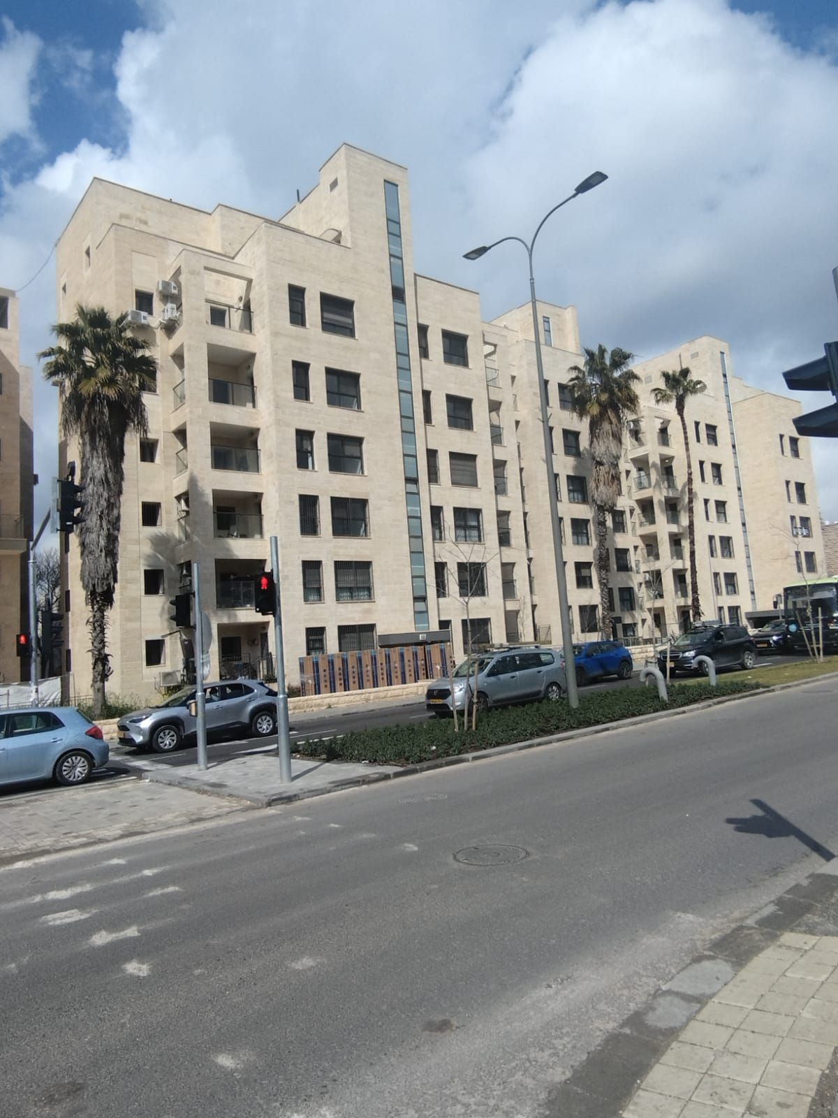 A Jerusalem stone apartment building on a tree-lined street