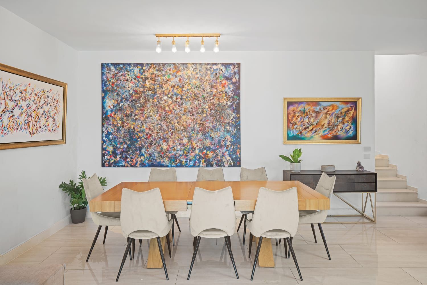 A finished dining room with a long wooden table and original artwork