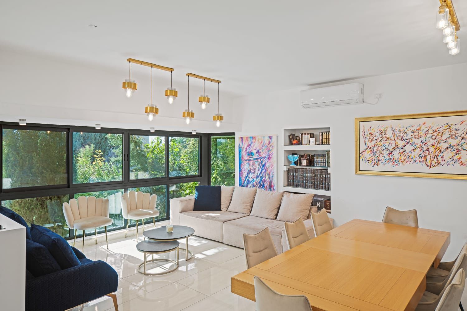 A furnished living room with large windows onto greenery